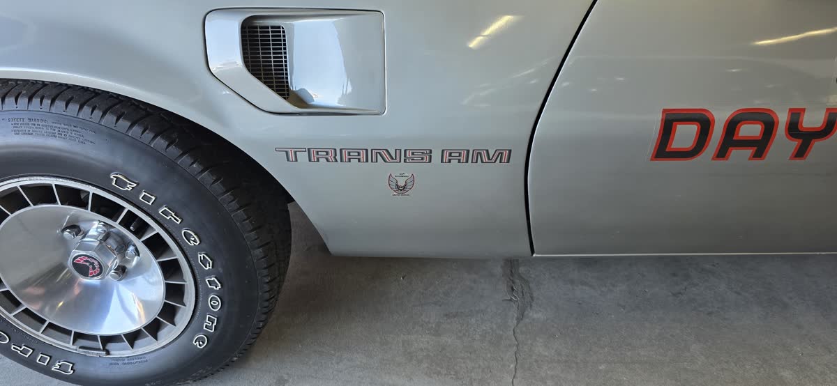 Trans Am fender script and bird emblem on a silver car. Reference for trim literacy, not a failed order photo.